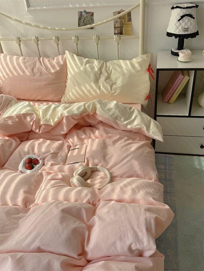 Pink bedding set on a bed with a nightstand in the background