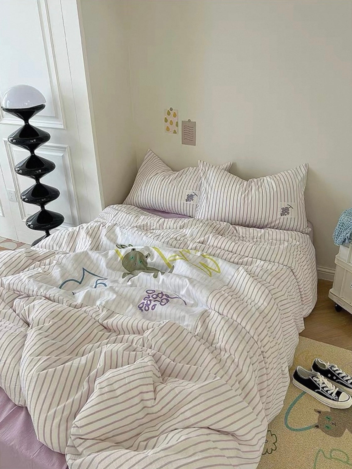 Purple striped Danish pastel bedding shown across a bed beneath small wall prints.