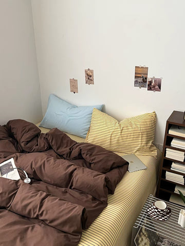 Dark brown bedding set with brown duvet cover, striped flat sheet, pale blue pillowcase and striped pillowcase