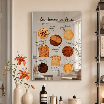 A framed wall art print featuring a whimsical dessert-themed poster titled 'Room Temperature Dessert' hangs on a beige wall in a styled room. The poster shows illustrated baked goods like cookies, cakes, and pastries with handwritten labels.