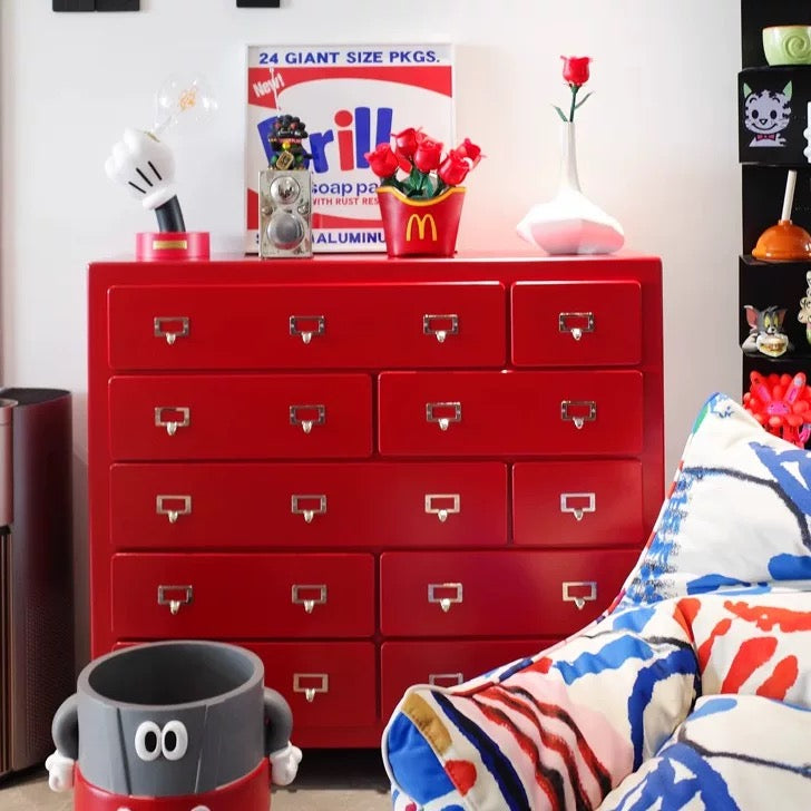 Red dresser with various items including a McDonald's container and a 'Brill' soap package in a room.
