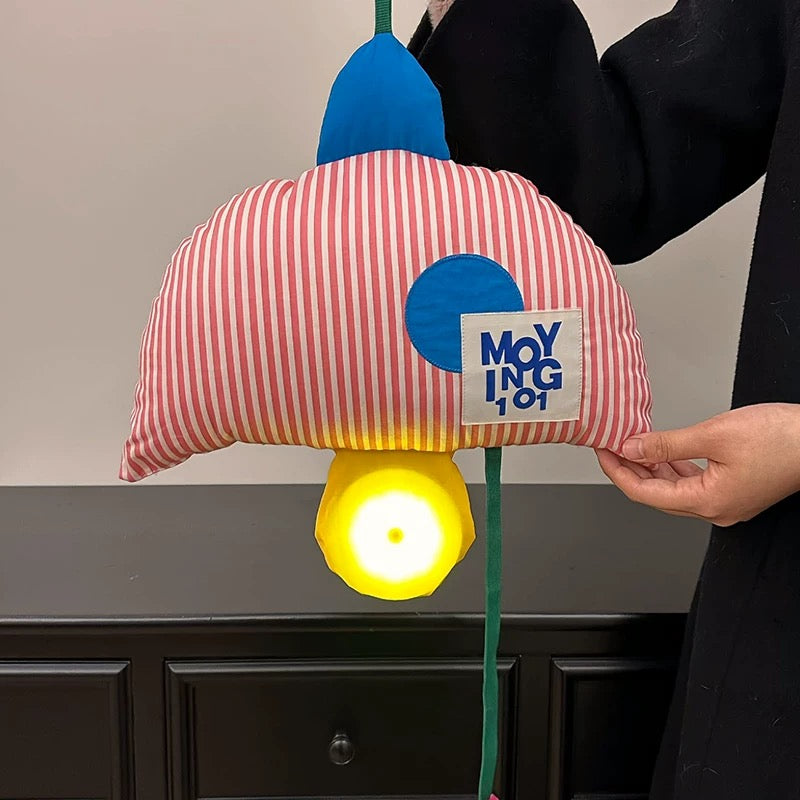 Colorful lamp with a striped shade and blue accents, held by a person.