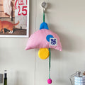 Colorful cat toy with striped pink umbrella and blue and yellow accents hanging on a hook.