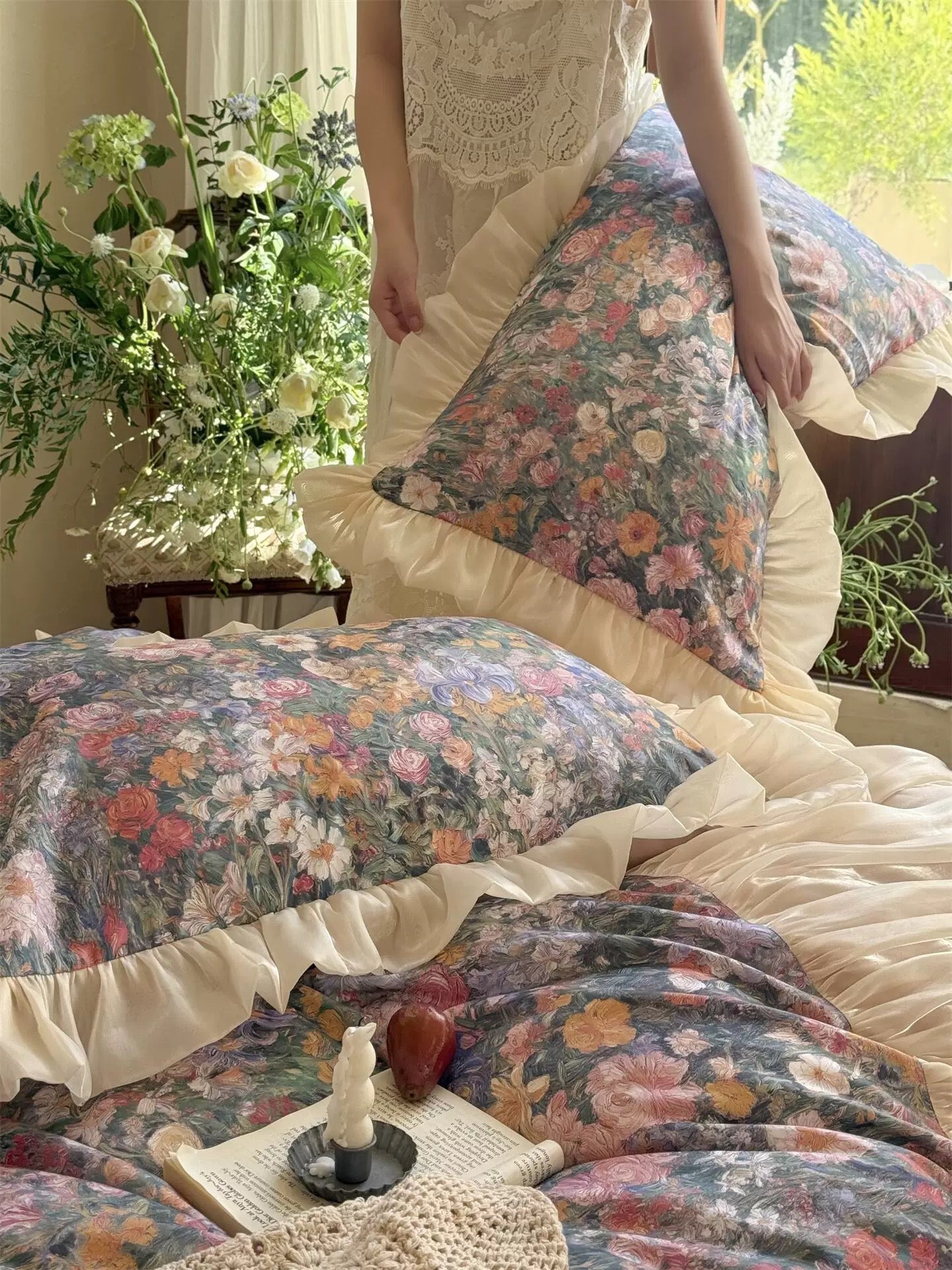 Floral bedding with ruffled edges on a bed, surrounded by greenery.