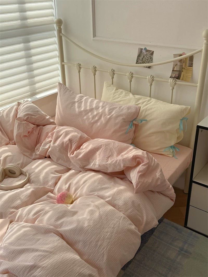 Bed with pink bedding and pillows in a softly lit room