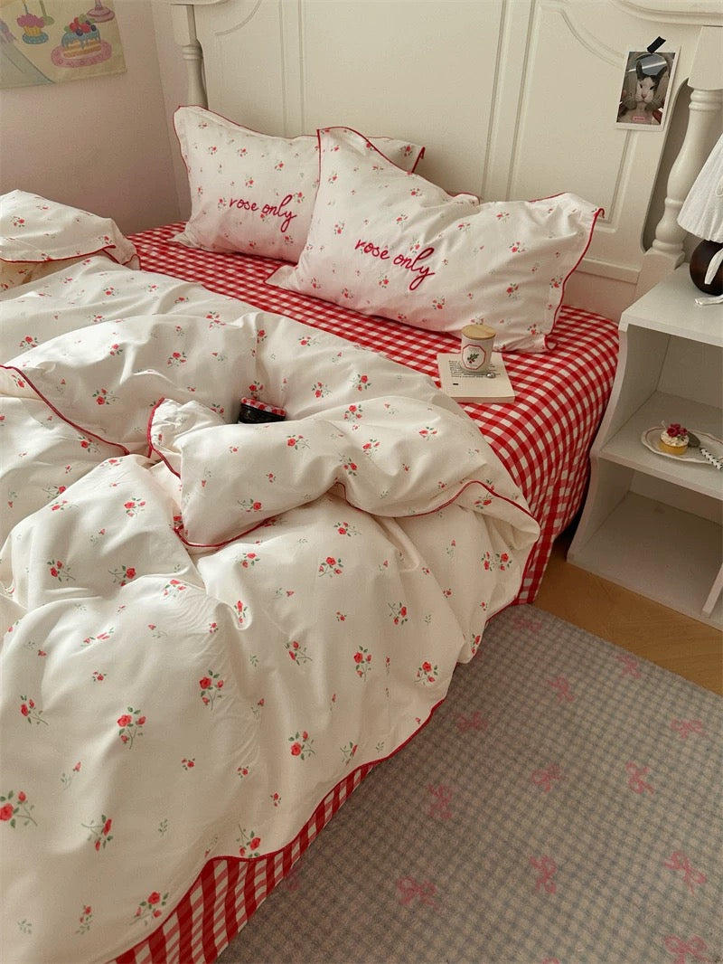 Bed with white bedding and red checkered pattern, featuring 'love only' text on pillows.