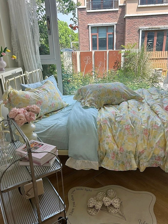 Side view of pastel floral bedding beside a window and metal bedside table