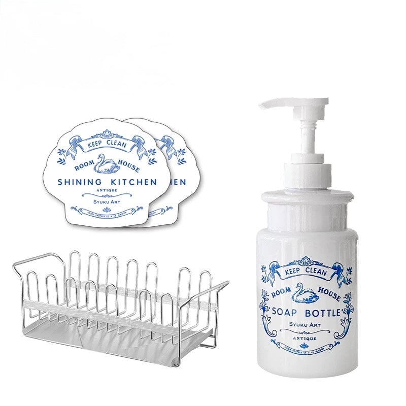 The floral soap dispenser appears beside two matching sponges and a rectangular stainless steel draining rack.