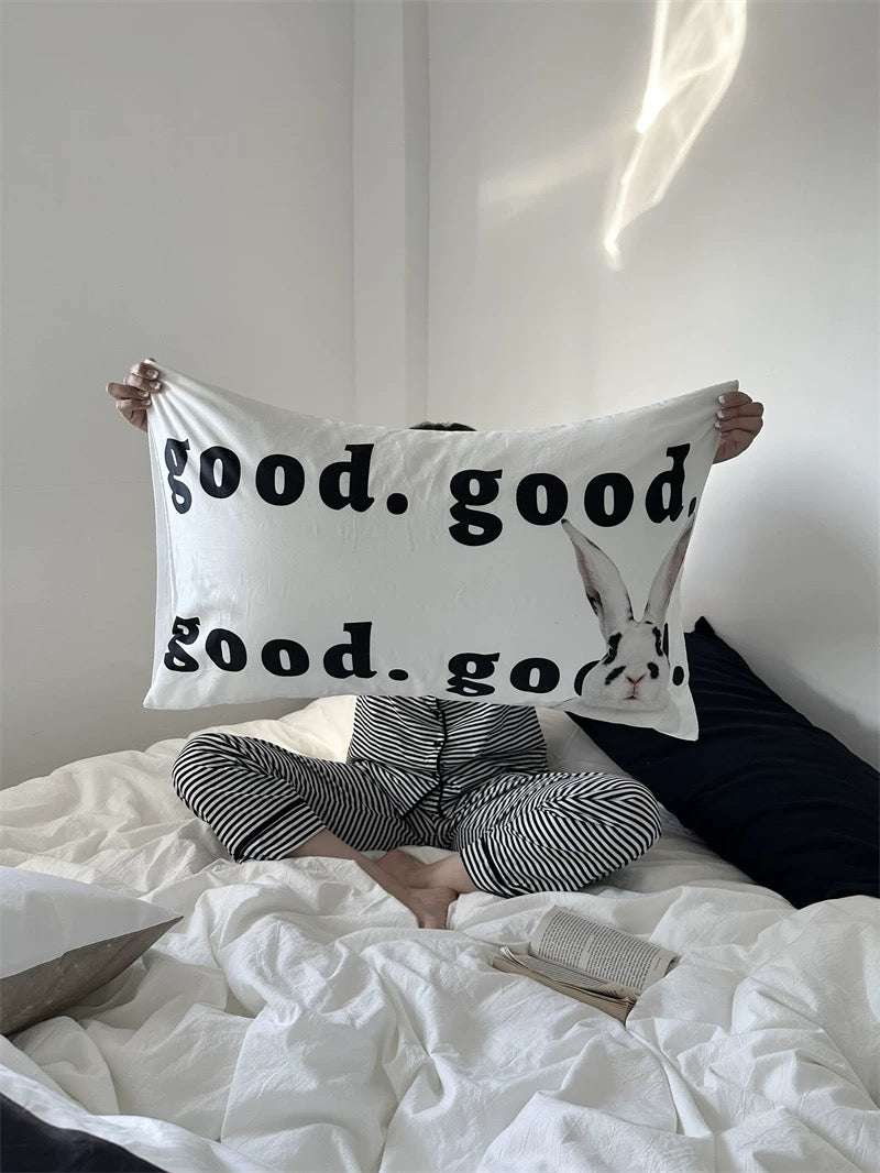 Person holding a pillow with 'good. good good. go' text on a bed.
