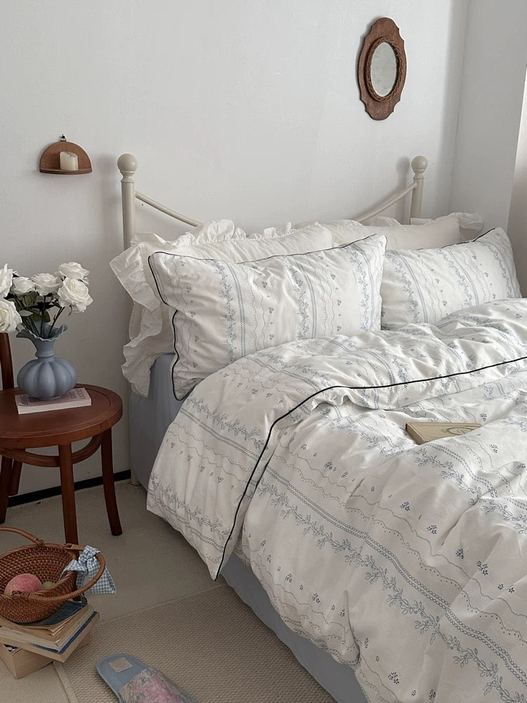 Bedroom with floral bedding and a side table.