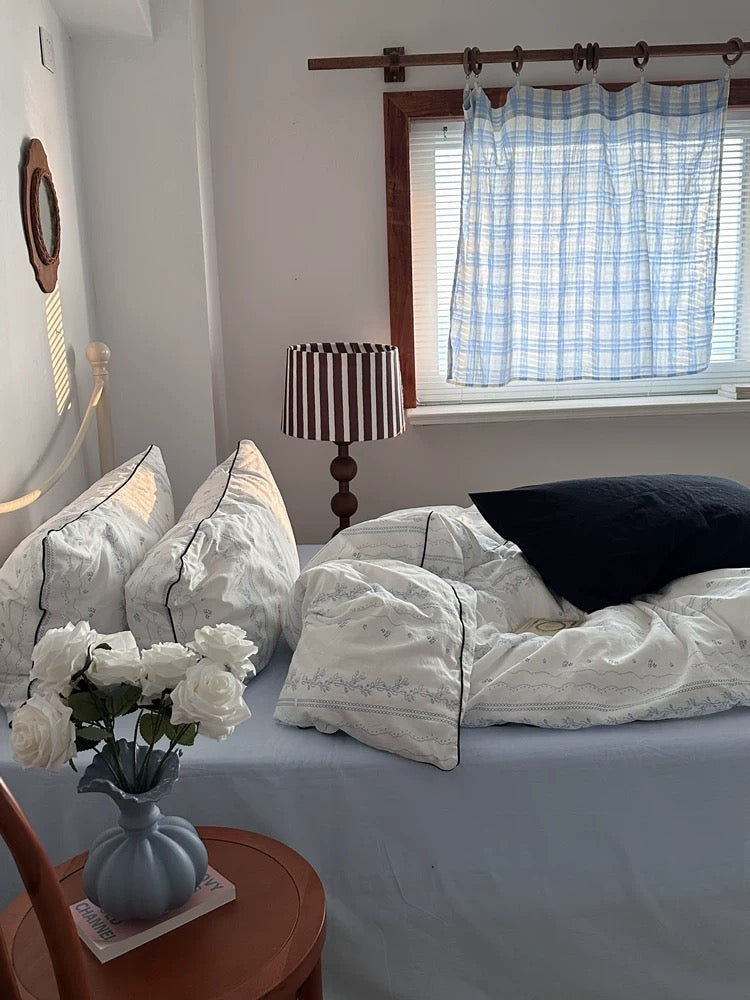 Bedroom with a bed, lamp, and window with curtains