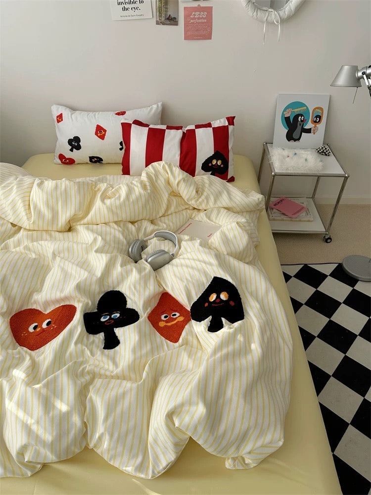 Embroidered poker card design on duvet cover, shot in aesthetic bedroom setting with cozy warm lighting.