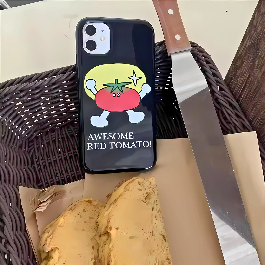 Person holding a phone with a cartoon tomato design on a black case.