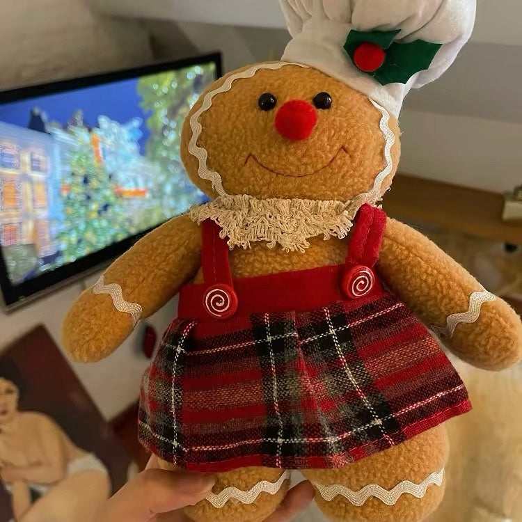 The gingerbread woman wears a white chef hat, red suspenders and a plaid skirt over her brown cookie body.