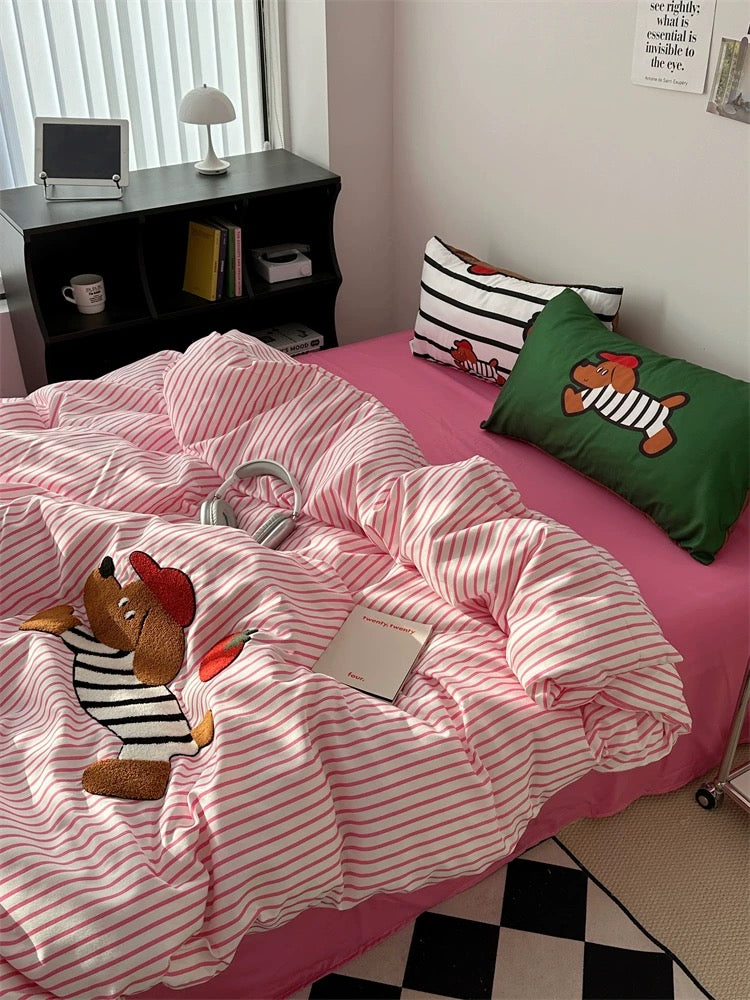 Bed with pink and white striped bedding featuring cartoon dog characters, in a room setting.