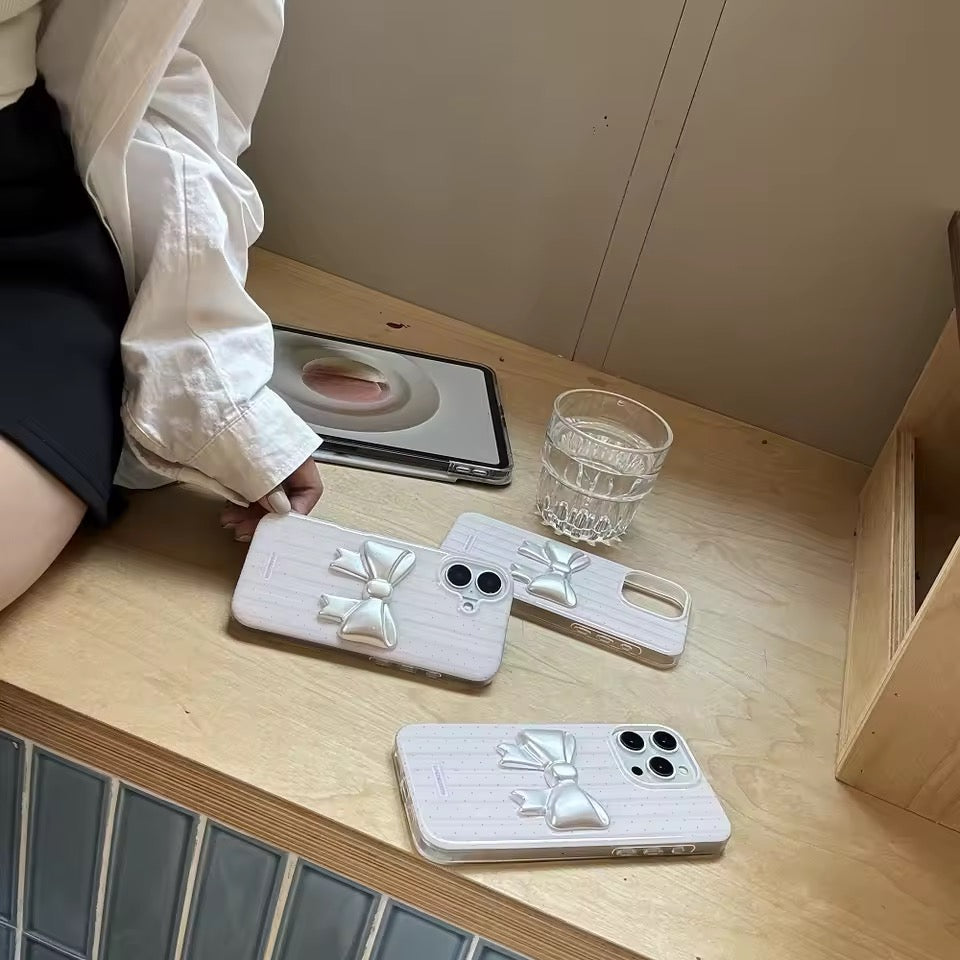 Person holding a phone case with bow design on a wooden table