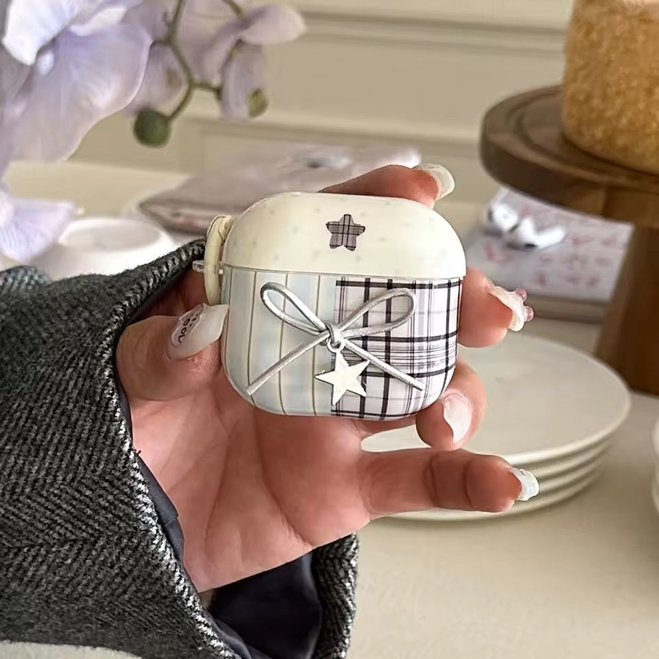 Hand holding a small decorative item with plaid pattern and star designs, blurred indoor background
