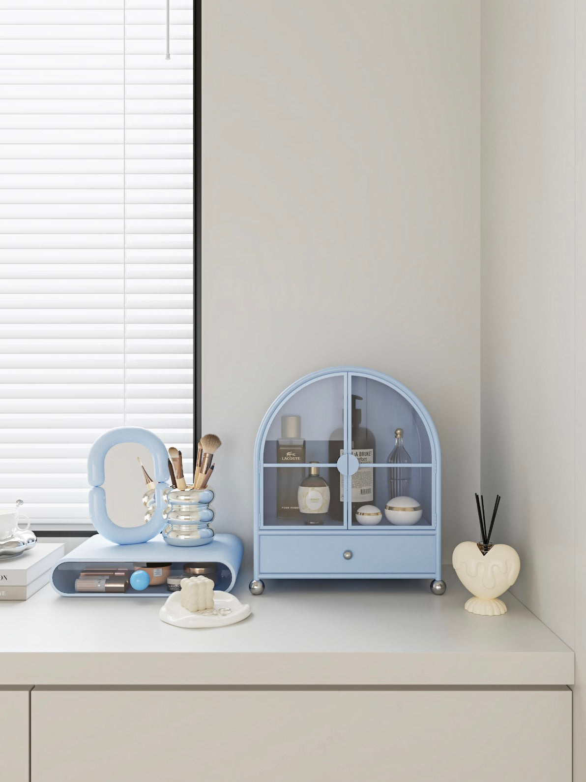 A blue glass makeup organizer faces forward on a dresser, with a drawer below the bottle display.