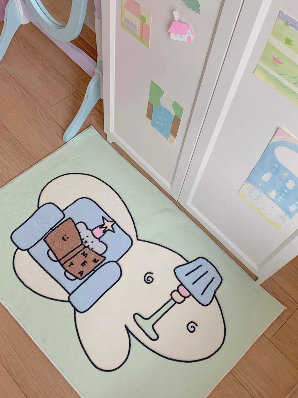 A green reading elephant rug lies beside a checked chair, showing a blue armchair and a drawn lamp.
