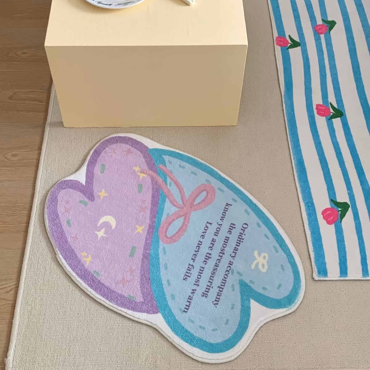 Pastel heart bath mat with aqua, pink and lavender print beside a striped cherry rug