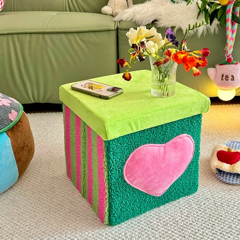 Green storage ottoman with heart detail styled beside a sofa