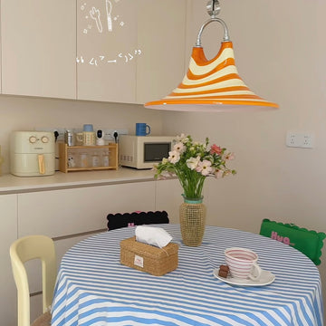 Dining area with a striped tablecloth, flowers, and kitchen appliances.