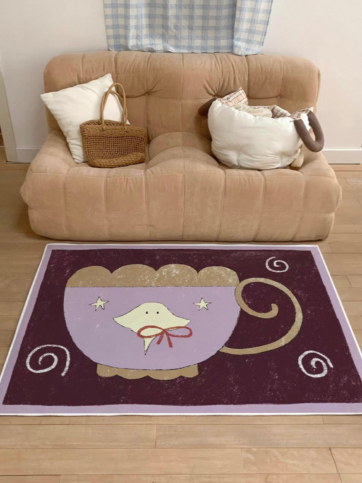 A purple rug with a large lilac cup and pale spiral details sits directly in front of a tan sofa.