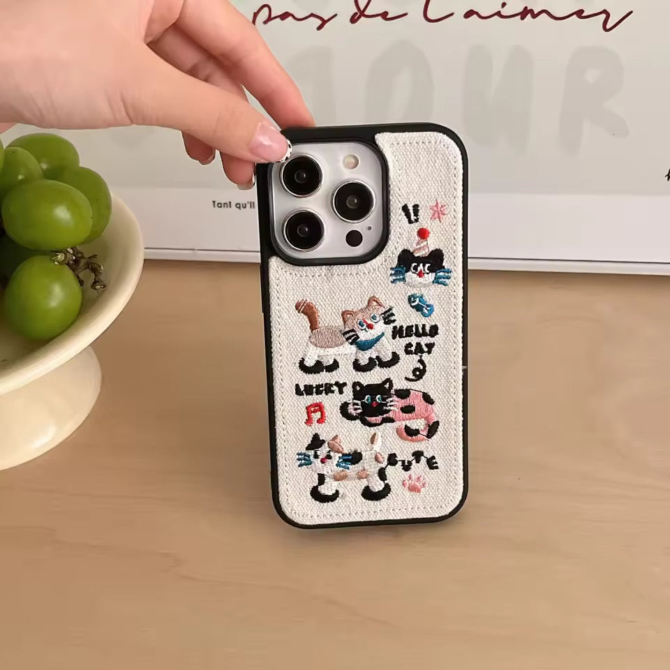 Phone case with embroidered cat designs on a beige background