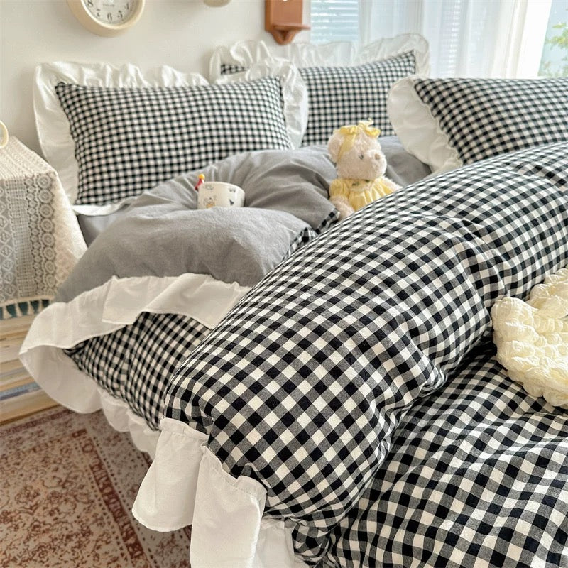 Bed with black and white checkered bedding and gray pillows in a bedroom setting.