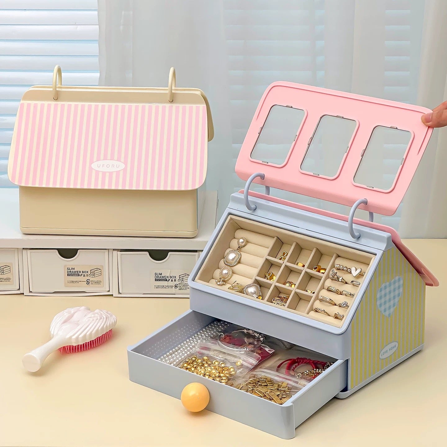 Jewelry organizer with pink lid and beige body, filled with jewelry on a light surface.