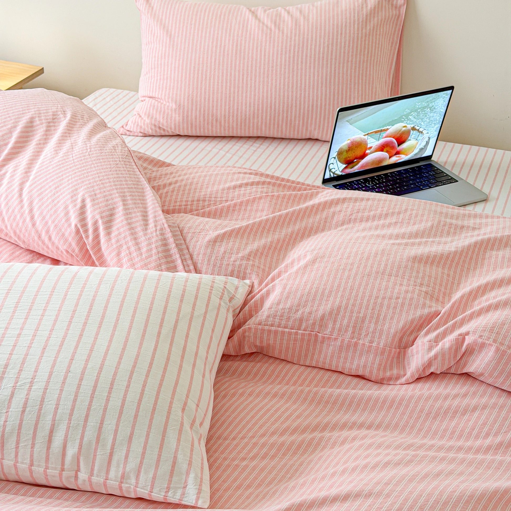 Korean minimal bedroom featuring soft pink striped bedding and bright natural lighting with timeless cotton texture.