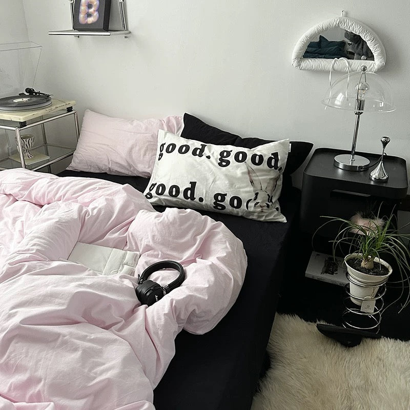 Cozy pastel pink bedding styled with “good.good.” pillow and neutral tones.