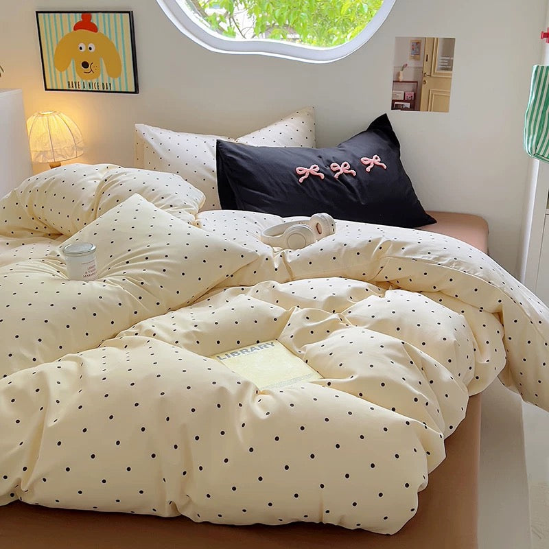 Close-up of the brown polka dot comforter with a yellow “LIBRARY” book and a soft girl room vibe