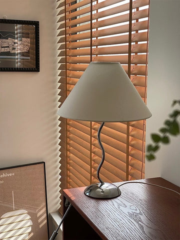 Table lamp on a wooden surface with blinds in the background