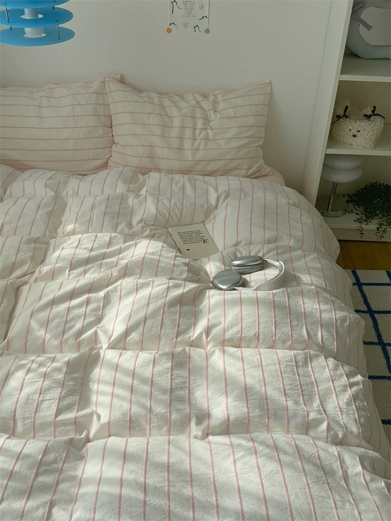 Bed with striped bedding and pillows in a room setting.