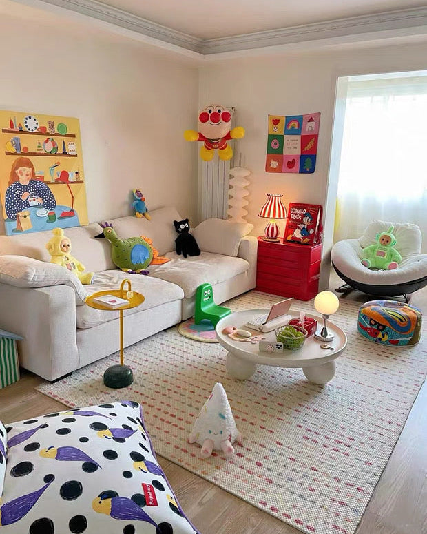 Children's playroom with toys and furniture on a light wood floor.