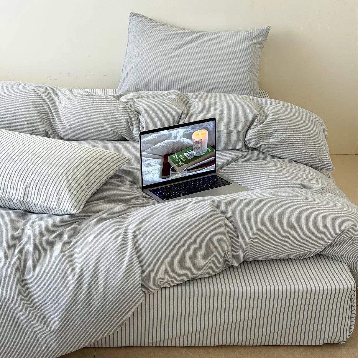 Modern classic gray striped bedding displayed with neutral decor and layered cotton comfort on wooden platform bed.