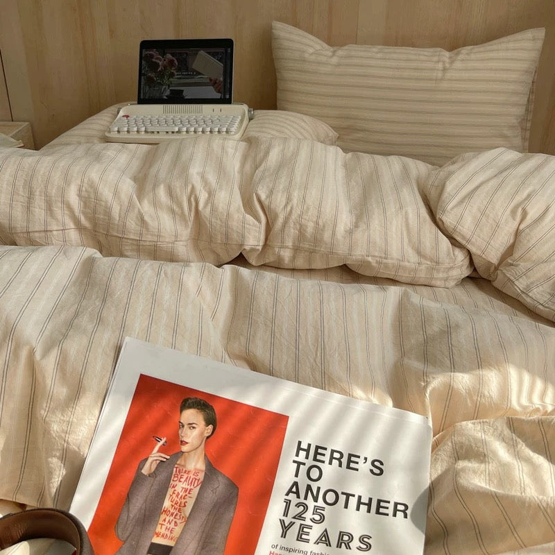 Laptop on a bed with a magazine titled 'Here's to Another 125 Years' in the foreground.