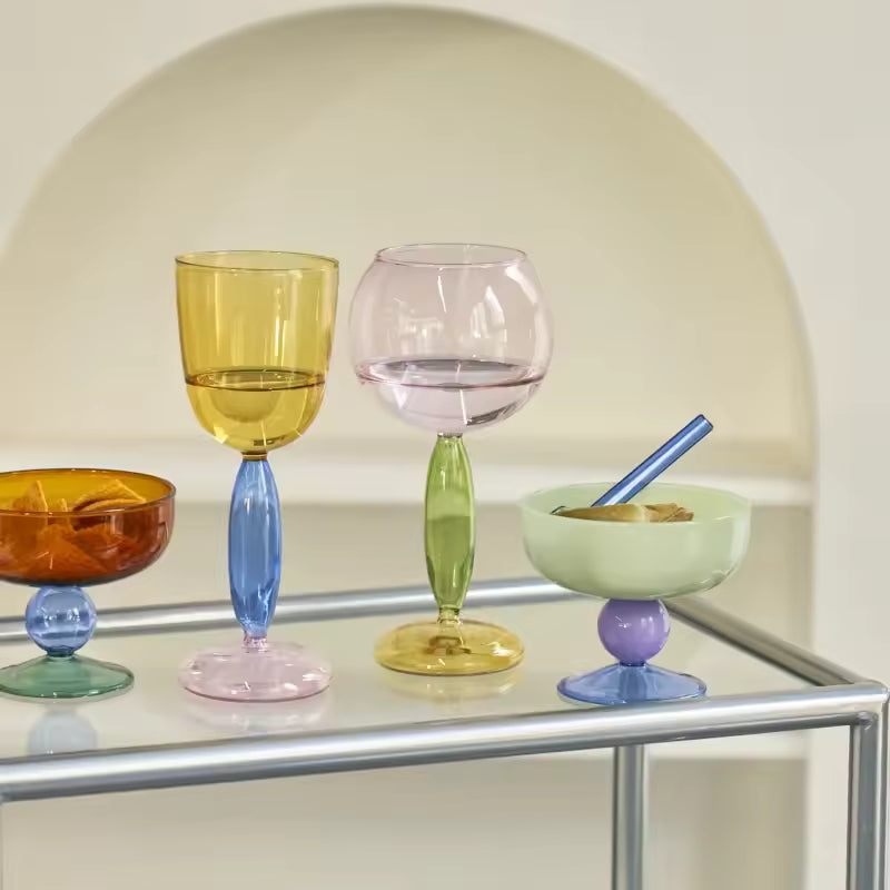 Set of colorful glassware on a reflective surface with a neutral background