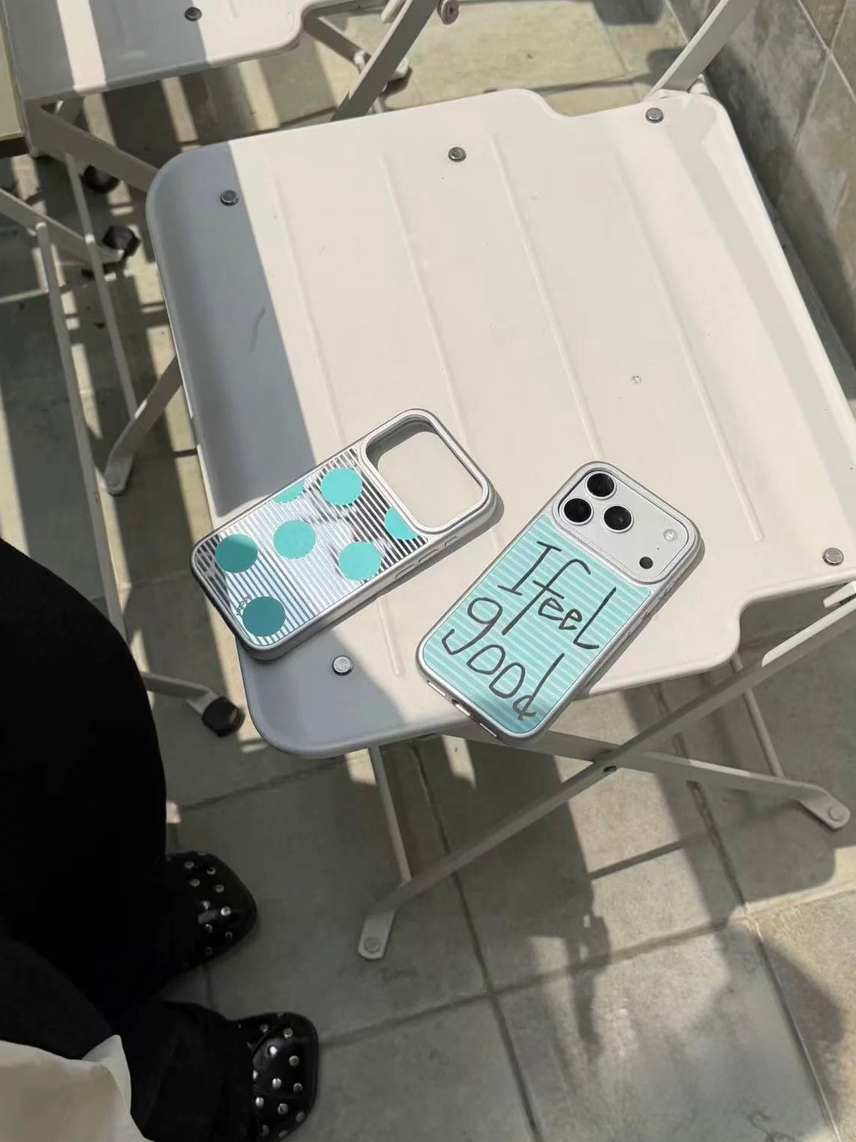 Two magnetic iPhone case designs rest side by side, showing aqua stripes, silver borders and large aqua dots.