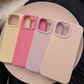 Four phone cases in beige, pink, and purple on a black surface
