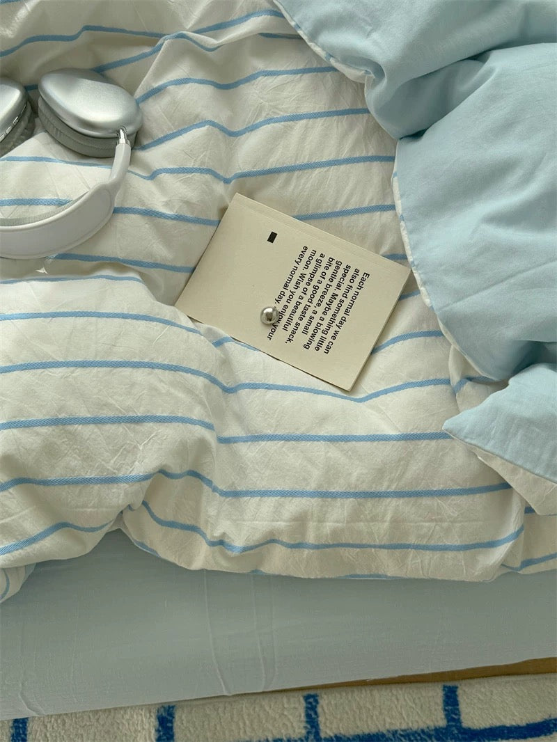 Light blue and white striped fabric with a tag on a bed