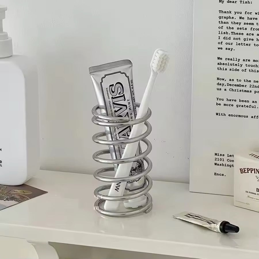 Holder displayed on a bathroom countertop with toothbrushes and toothpaste