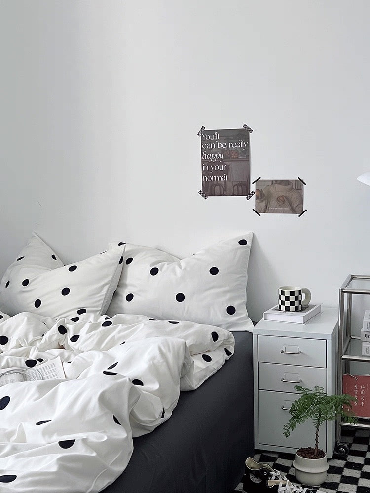 Bedroom with polka dot bedding and a nightstand with decor items.