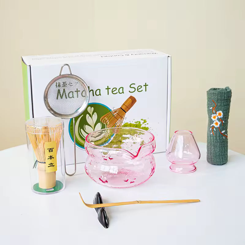 Matcha tea set with various tools and a branded box on a white surface.
