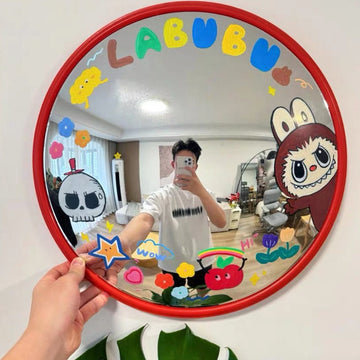 Person holding a round mirror with colorful decorations and cartoon characters.