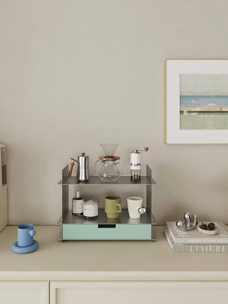 Mint green desktop shelf with a drawer styled with a coffee set on a cream cabinet and a framed sea print