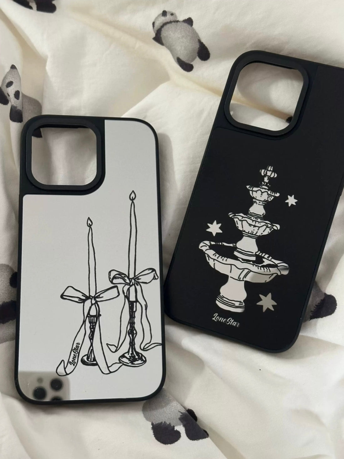 A dark coquette phone case pair with silver bow candles and a black star fountain, both edged in black.
