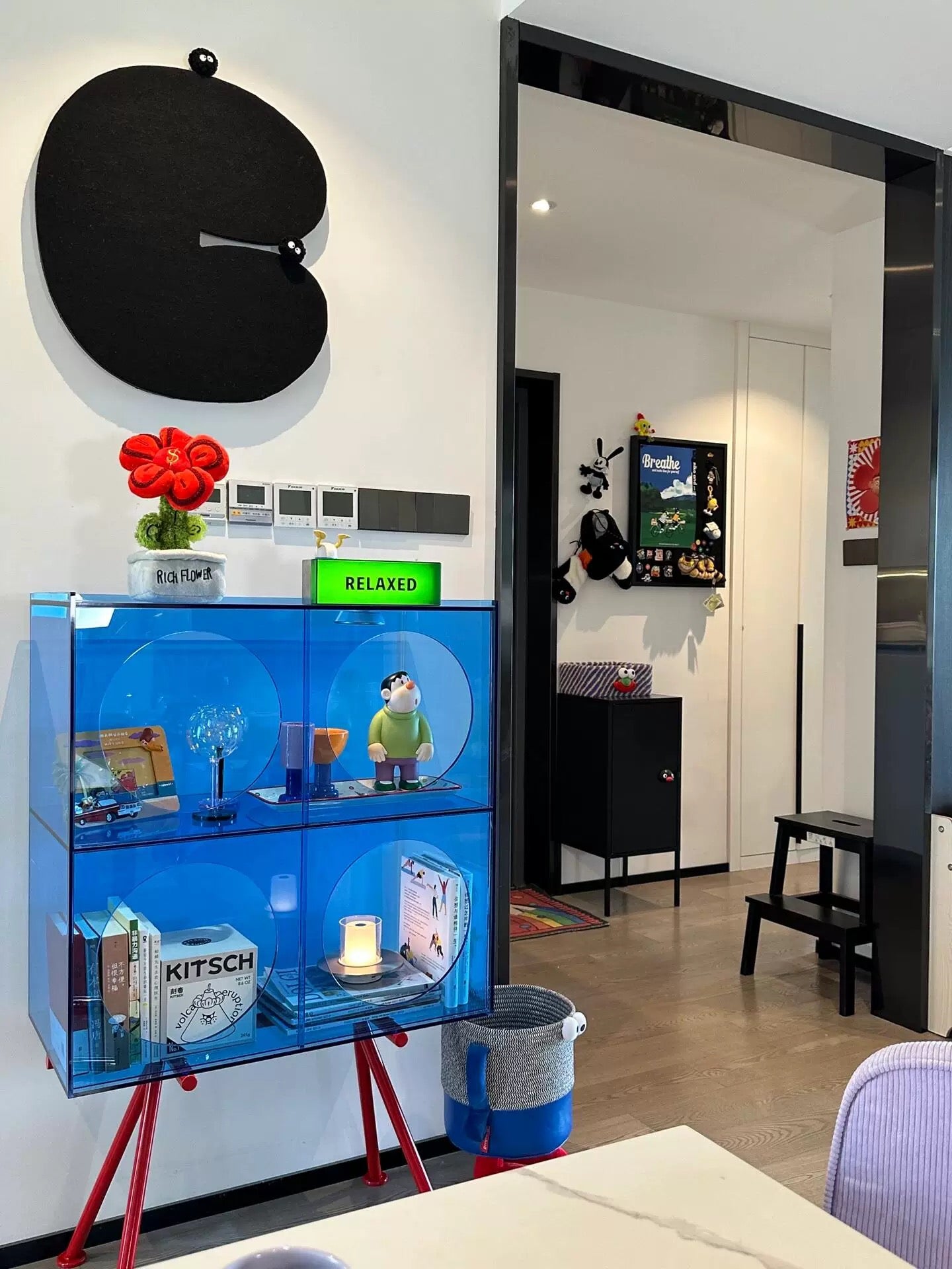 Modern interior with a blue display cabinet, red chair, and decorative items.