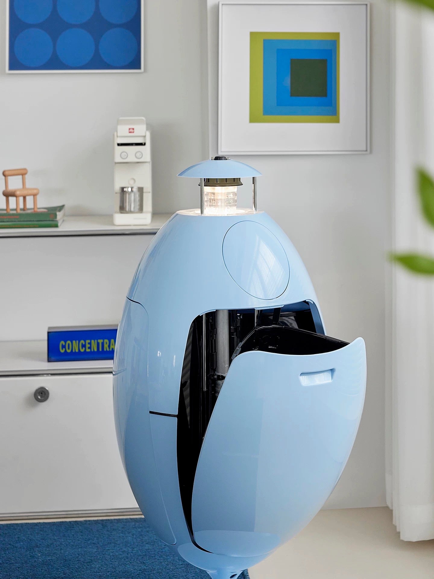 Modern kitchen setting with a blue egg-shaped appliance on a countertop.